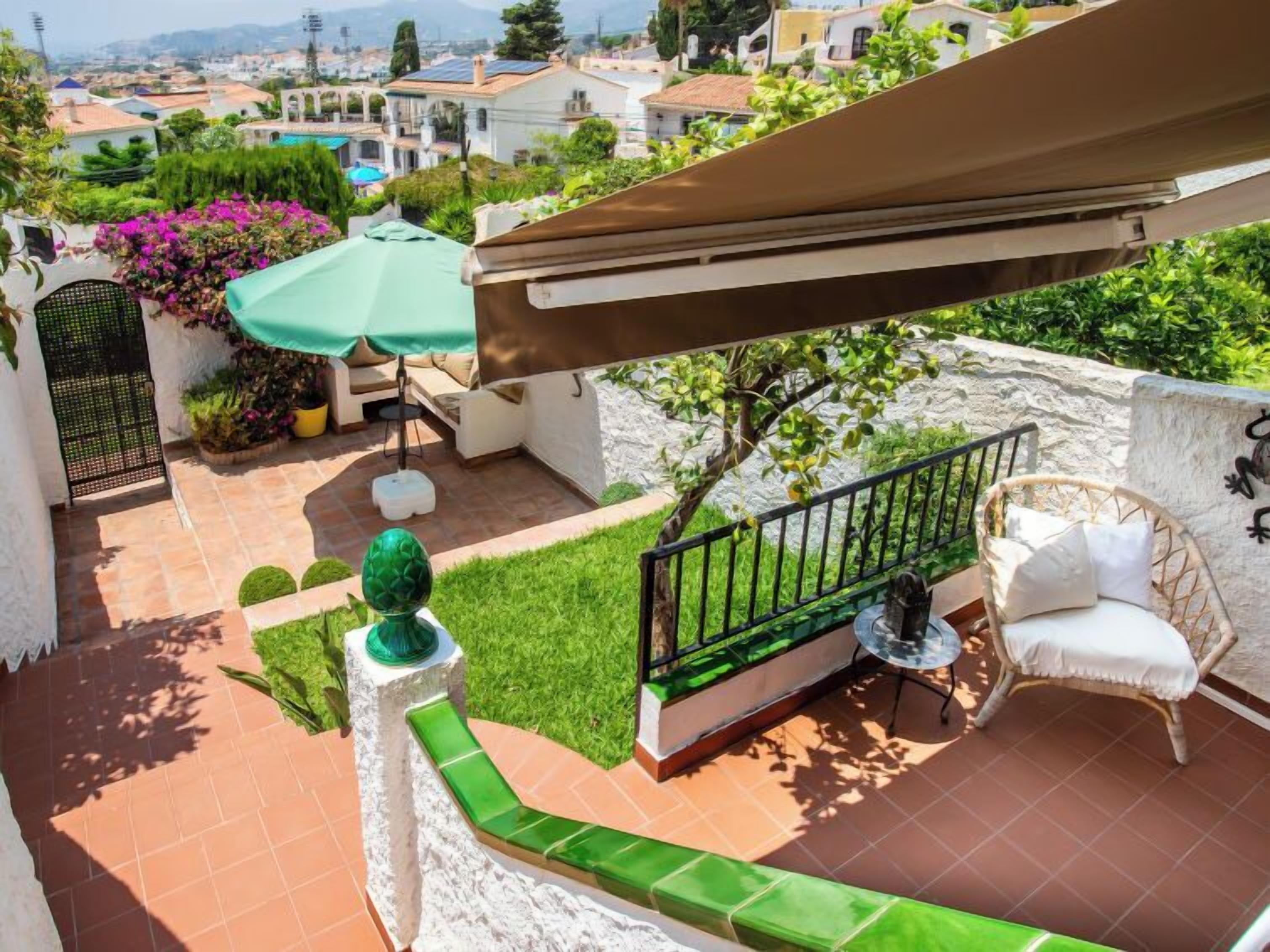 A rooftop patio with a green lawn, outdoor furniture, and a view of the cityscape.