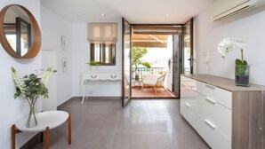 A modern kitchen with white cabinetry, a round mirror, and a dining area with a table and chairs. - Limoneros by Interhome (Nerja)