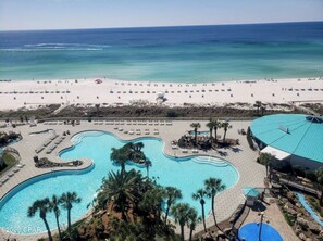 Un resort con un amplio área de piscina, una playa y un edificio de techo azul.