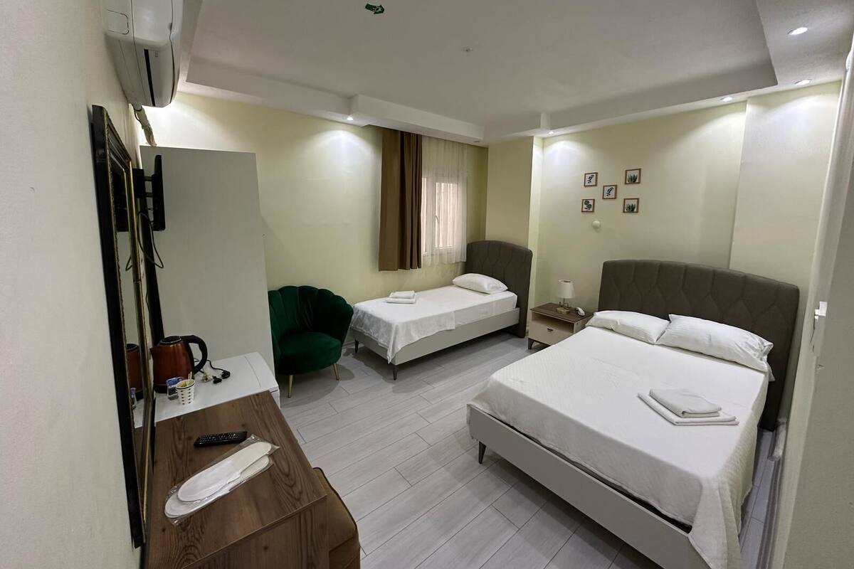 Habitación de hotel con cama, escritorio, teléfono, silla y espejo.