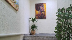 Una escalera con una planta en la barandilla, un cuadro en la pared y otra planta a la derecha.