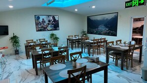Un comedor con varias mesas y sillas, un cuadro grande en la pared y vistas a un paisaje por la ventana.