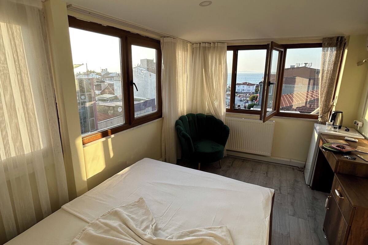 Una habitación de hotel con cama, una silla, un escritorio y vista a la ciudad.
