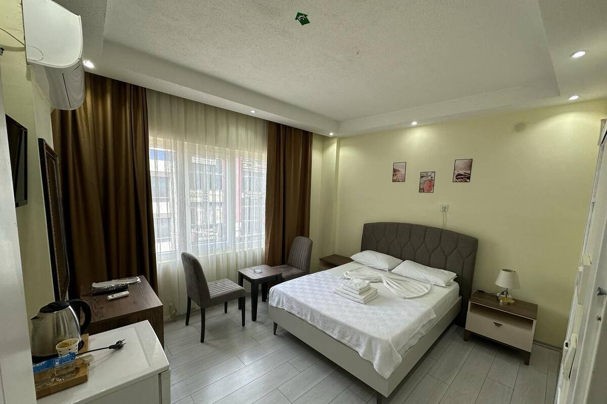 Una habitación de hotel con cama, escritorio, silla, mesita de noche y lámpara.