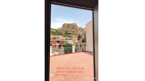A view from a building terrace overlooking a rocky hill and a town.
