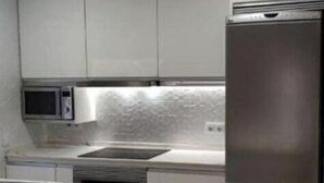 A modern kitchen with white cabinets, a stainless steel refrigerator, and a marble island.