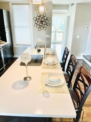 Enjoy meals in the kitchen with a central island and dining area featuring a long table and comfortable seating.