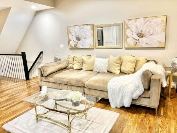 Cozy living space with a beige sofa, throw blanket, and glass coffee table.