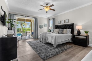 A bedroom with a bed, bedside table, lamp, and a ceiling fan. - Disney Dreams Getaway | Heated Pool, Hot Tub & Magical Family Escape (Kissimmee)