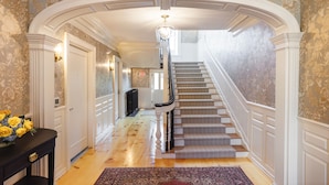 A grand hallway with a staircase, ornate ceiling, and floral wallpaper. - The Davenport Inn (Portsmouth)
