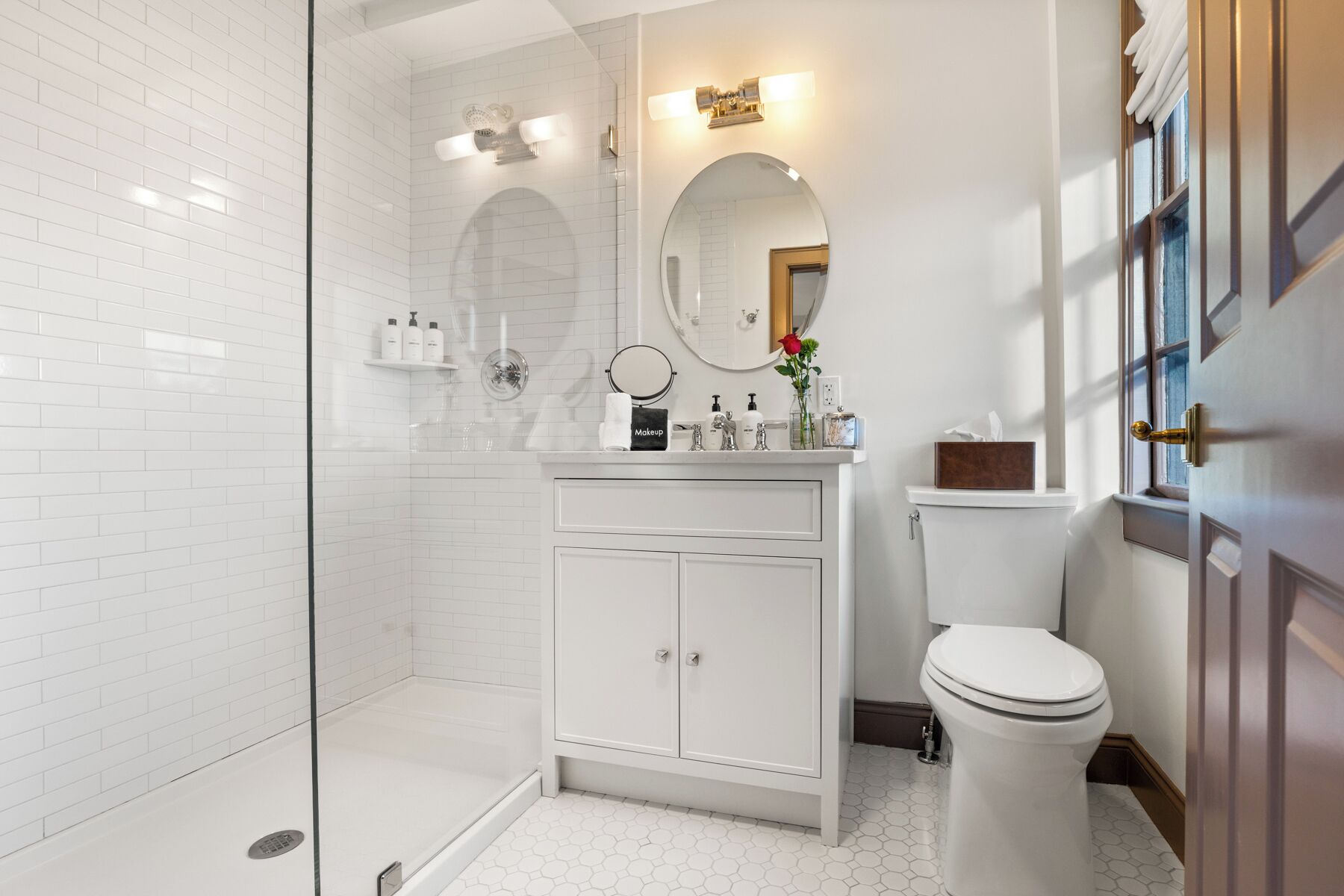 A modern bathroom with a glass shower enclosure, a white vanity with a mirror, and a toilet.