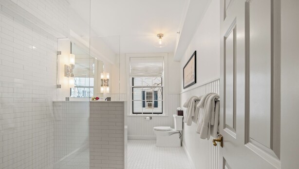 A modern bathroom with white tiled walls, a hexagonal floor pattern, a glass shower enclosure, a toilet, and a towel rack. - The Davenport Inn (Portsmouth)