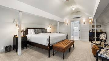A spacious bedroom with a large bed, a bench, a desk, and a chair.