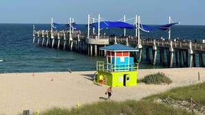 A pier extending into the ocean with a lifeguard station and beach area.