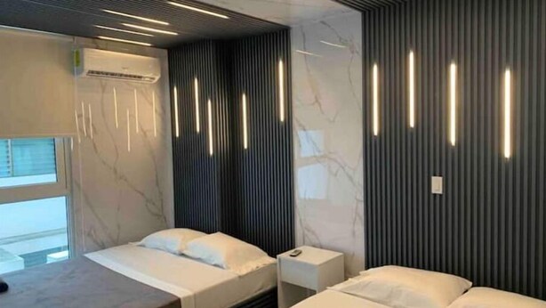 Ein modernes Hotelzimmer mit zwei Betten, einem großen Fenster und einer integrierten Klimaanlage.