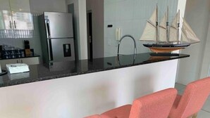 Eine moderne Küche mit integriertem Kühlschrank, einer Spüle und einer Bar mit zwei pinkfarbenen Barhocker.