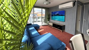 Una sala de estar moderna con un televisor de pantalla plana grande, un sofá azul y una planta en maceta.