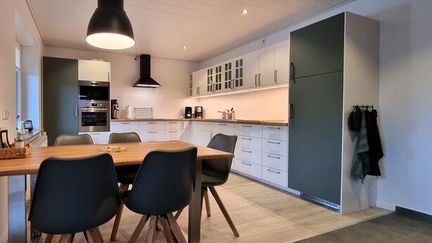 A modern kitchen with a wooden dining table, black chairs, and built-in appliances. - Heidezauber: Modern vacation apartment with terrace and fireplace (Uelzen)