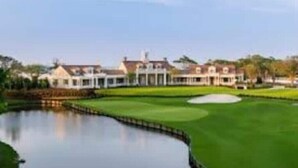 A golf course with a pond, clubhouse, and residential buildings in the background. - Marshfront Villa In The Trees - Near Beach & Bay
 (Edisto Island)