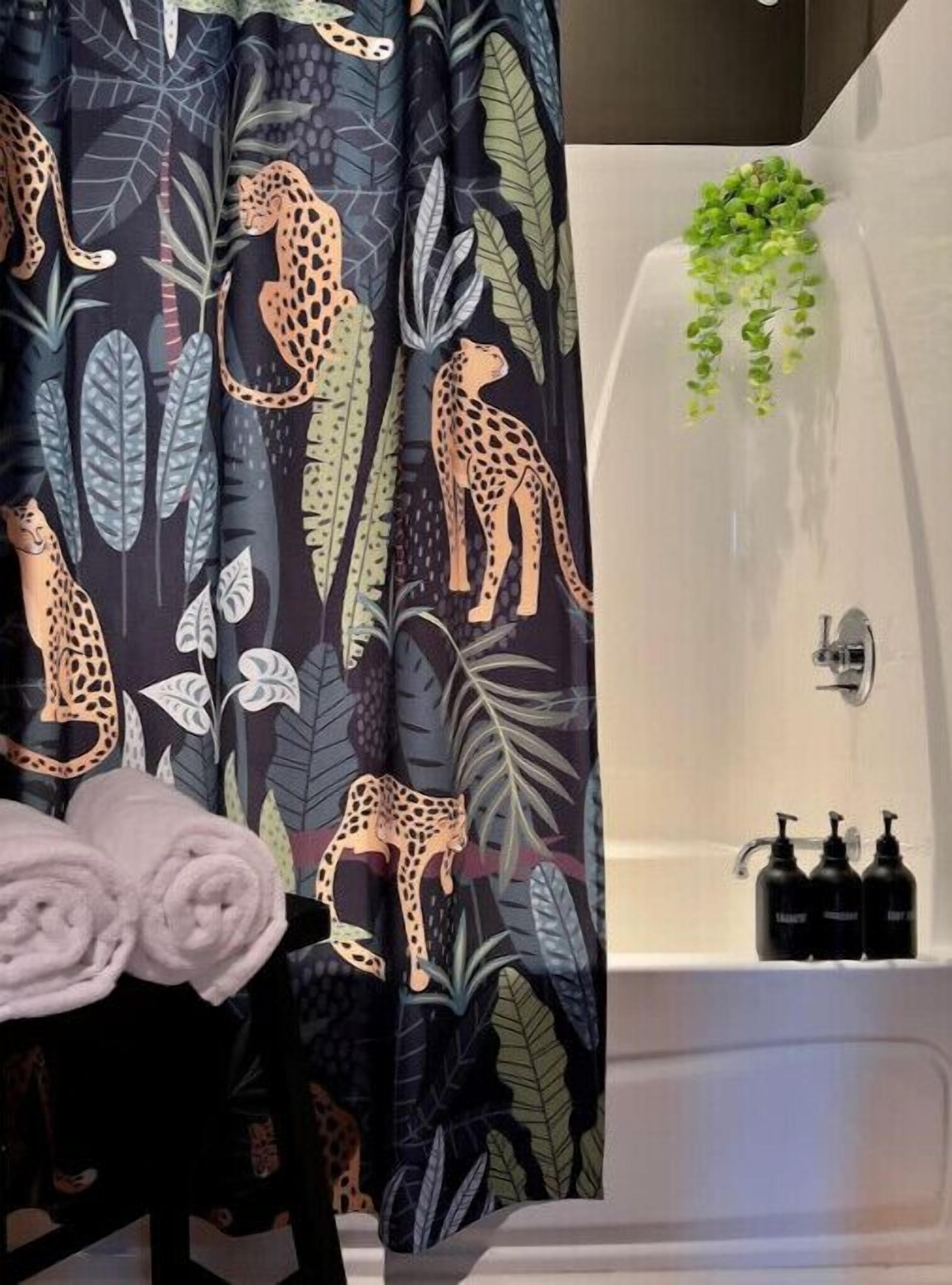 Une salle de bain avec un rideau de douche à motifs léopard, une baignoire blanche et une petite plante verte accrochée au mur.