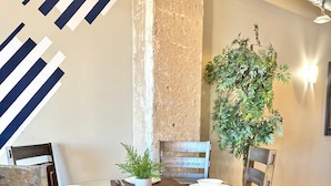 A dining area with a round glass table, wooden chairs, and a potted plant.