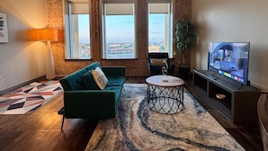 A modern living room with a green sofa, a round coffee table, and a TV on a stand.