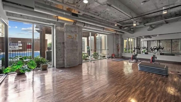 A spacious indoor area with large windows, wooden flooring, and exercise equipment.
