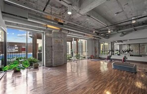 A spacious indoor area with large windows, wooden flooring, and exercise equipment. - 2BR | Stylish | Stylish Apartment | Newly updated! (Dallas)