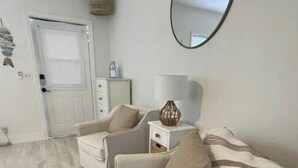 A modern living room with a sofa, a side table, a lamp, and a mirror.