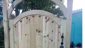 A wooden gate with a keypad lock, set in a wooden structure with a curved top.