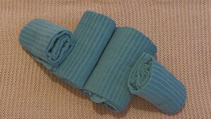 Een opgerolde blauwe handdoek op een geribbelde beige mat.