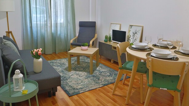 Een woonkamer met een bank, fauteuil, salontafel en eettafel, gedekt met borden, kommen en glazen.