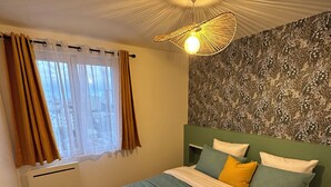 Un lit bien fait, avec une couette verte et blanche, un mur à motifs et un luminaire au plafond.