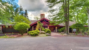 A lodge with a prominent red roof and a chimney, surrounded by lush greenery and trees.
