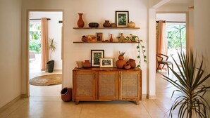 Una habitación con un armario de madera, estantes con adornos y una planta grande.