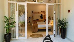 Una habitación con una cama, una silla y dos plantas en macetas.