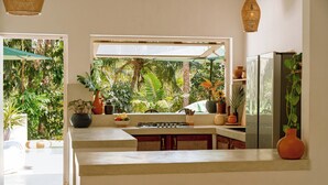 Una cocina con vistas a exuberante vegetación, estufa a gas y refrigerador.