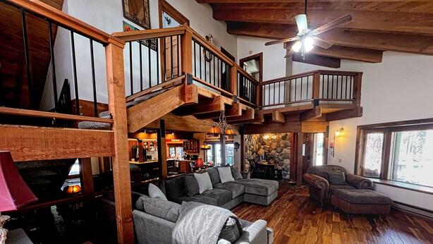 A spacious living area with a wooden staircase, a large sectional sofa, and a cozy fireplace. - Family Cabin in Graeagle CA w/King Bed & EV Charge (Graeagle)