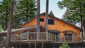 A wooden cabin with a deck and multiple windows, surrounded by tall pine trees. - Family Cabin in Graeagle CA w/King Bed & EV Charge (Graeagle)
