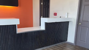 A reception area with a black and white counter, a door, and a red device on the wall. - Relax Inn & Suites (Mattoon)