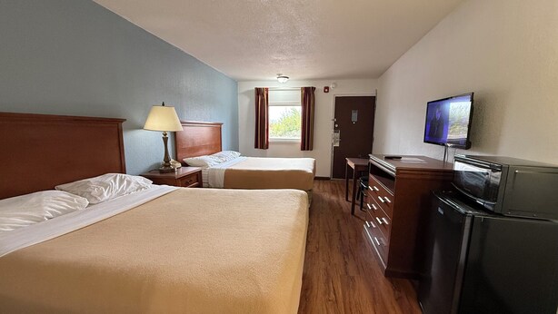 A hotel room with two beds, a desk, a television, and a refrigerator. - Relax Inn & Suites (Mattoon)