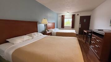 Quarto de hotel com duas camas, uma escrivaninha e uma cadeira.
