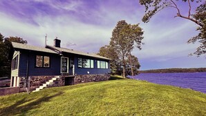 Ein Haus mit Steinfundament, einer Veranda und Blick auf einen See.