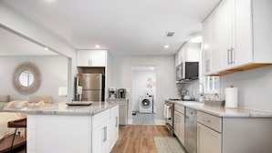 A modern kitchen with white cabinets, stainless steel appliances, and a central island.