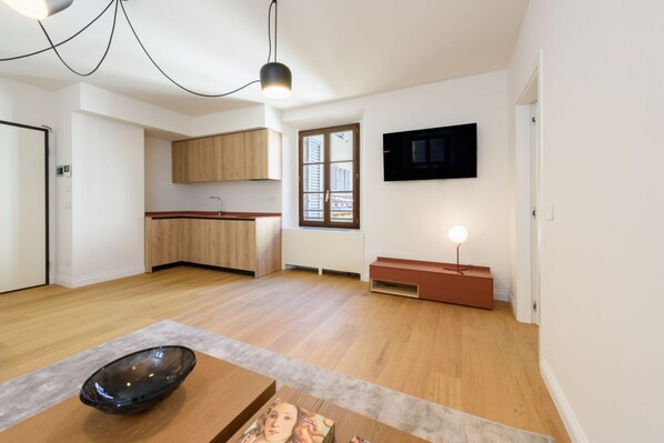 Une cuisine moderne avec des meubles en bois, un four encastré et un coin repas comprenant une table et des chaises.