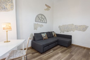 A modern living room with a grey sectional sofa, a white table, and a chair.