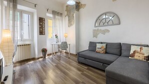A modern living room with a grey sofa, a small table, and a chair. There is a lamp, a radiator, and a map on the wall. - Artist's Refuge in Florence by Mmega (Firenze)