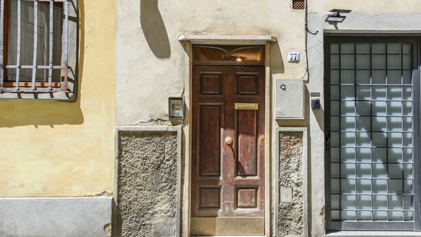 A wooden door with a brass handle, a mailbox, and a number plate '77' on a building facade. - Artist's Refuge in Florence by Mmega (Firenze)