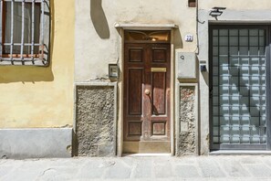 A wooden door with a brass handle, a mailbox, and a number plate '77' on a building facade. - Artist's Refuge in Florence by Mmega (Firenze)