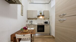 A compact kitchen with a dining table, chairs, a microwave, and a stove. - Artist's Refuge in Florence by Mmega (Firenze)
